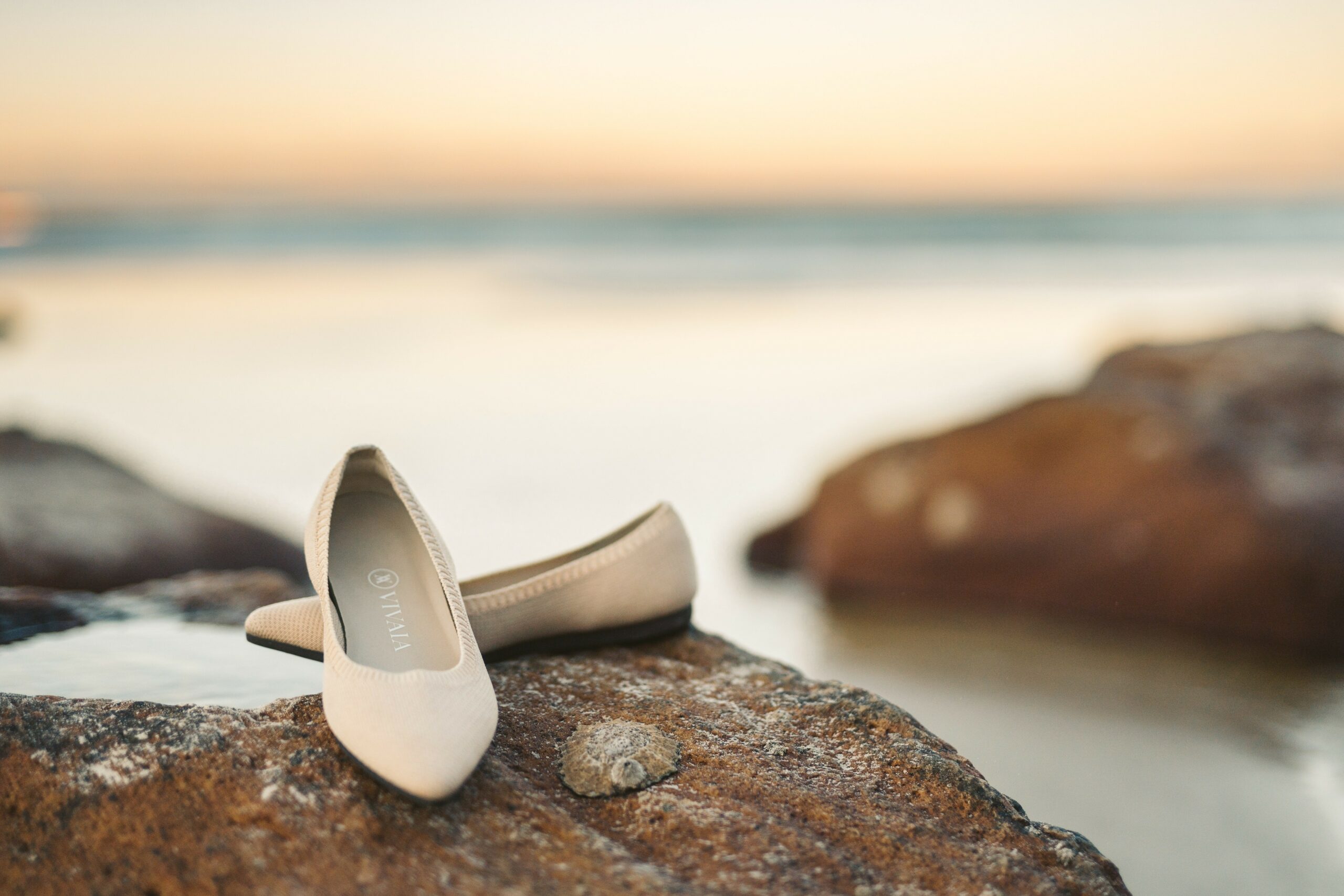 beige flat shoes sitting on rock near the ocean