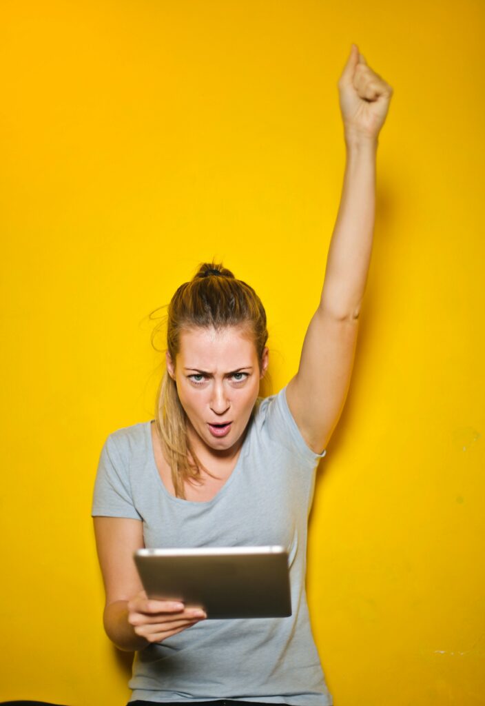 happy woman on a laptop in front of yellow wall