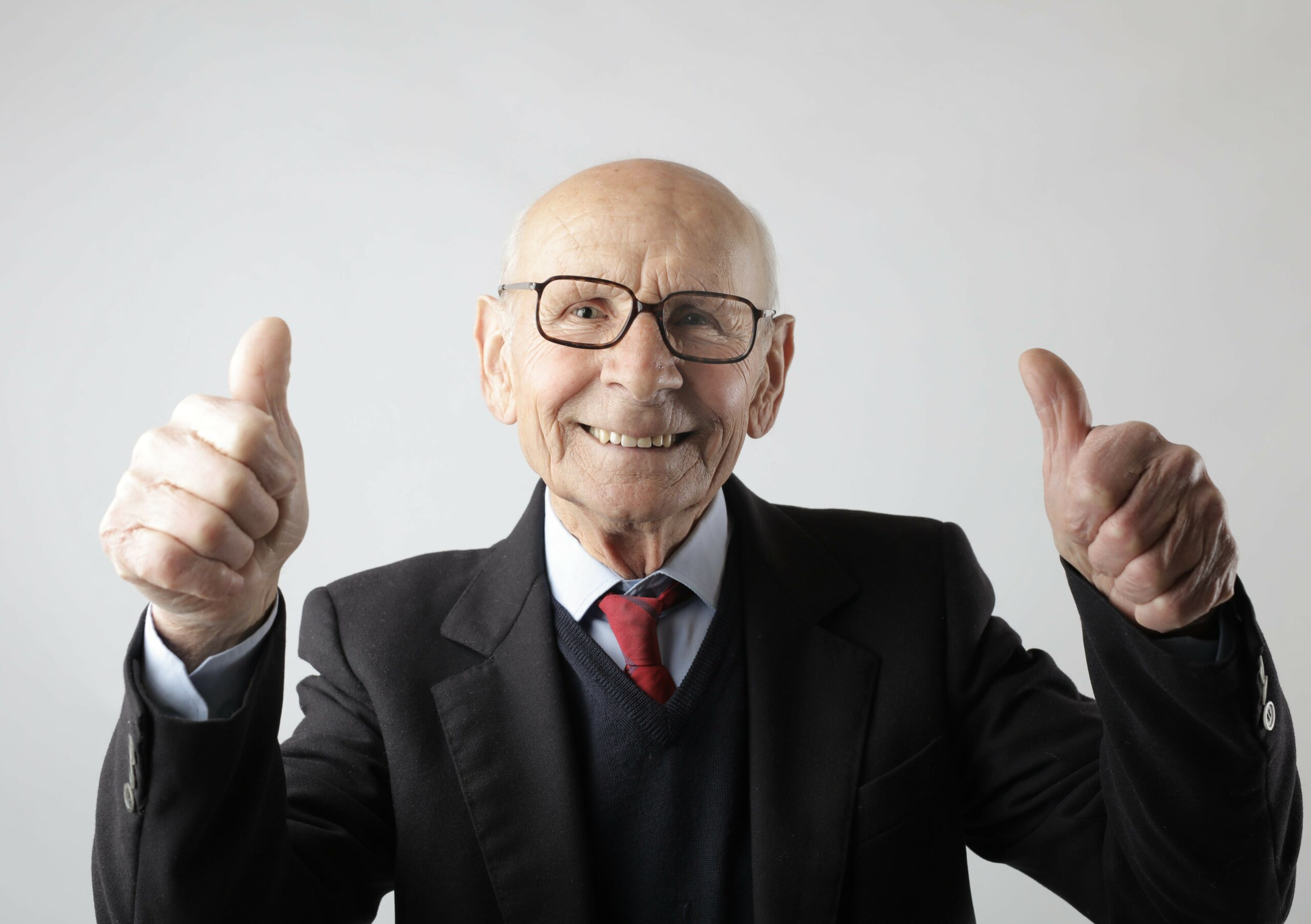 Male senior citizen holds two thumbs up and smiles