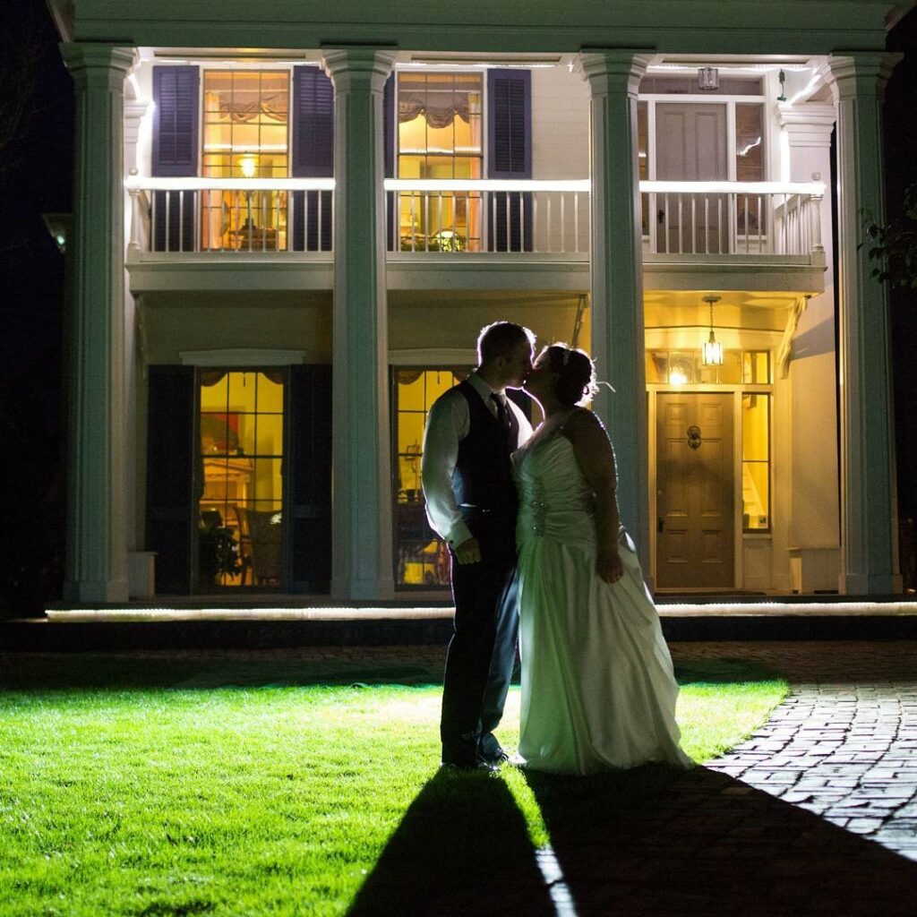 A newly married couple kisses at night in front of the Ainsworth House, a mansion dating to 1851