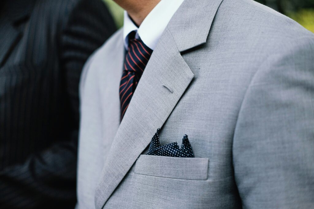 man wears a gray suit with a tie and stylish pocket square. Unsplash.com