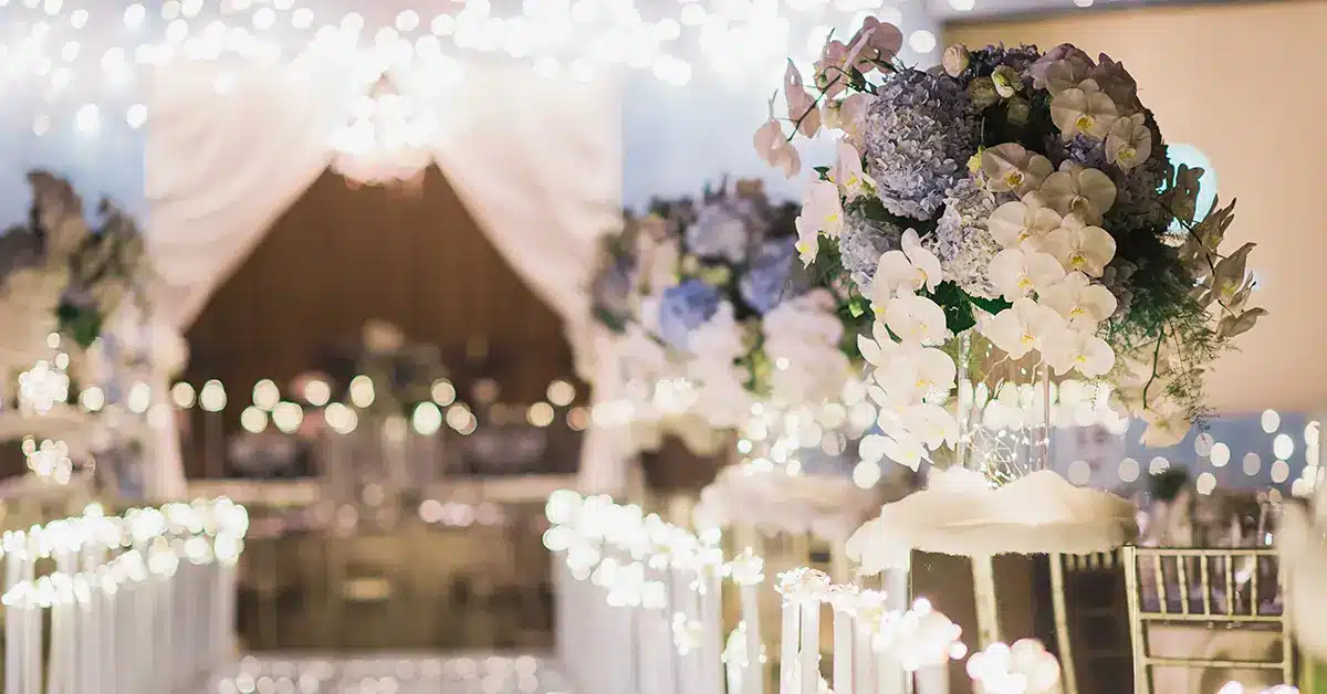 Elegant wedding aisle with floral arrangements and glowing string lights at sunset