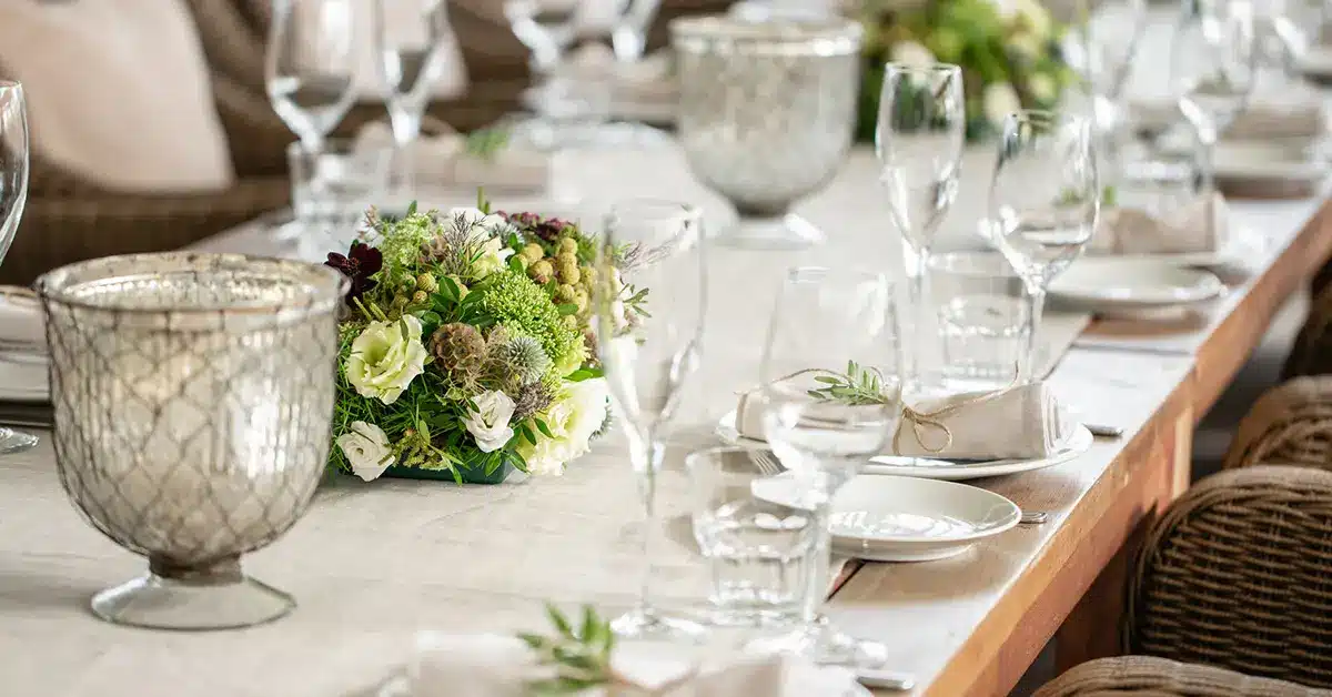Elegant indoor wedding reception table with floral centerpiece and glass candle holders